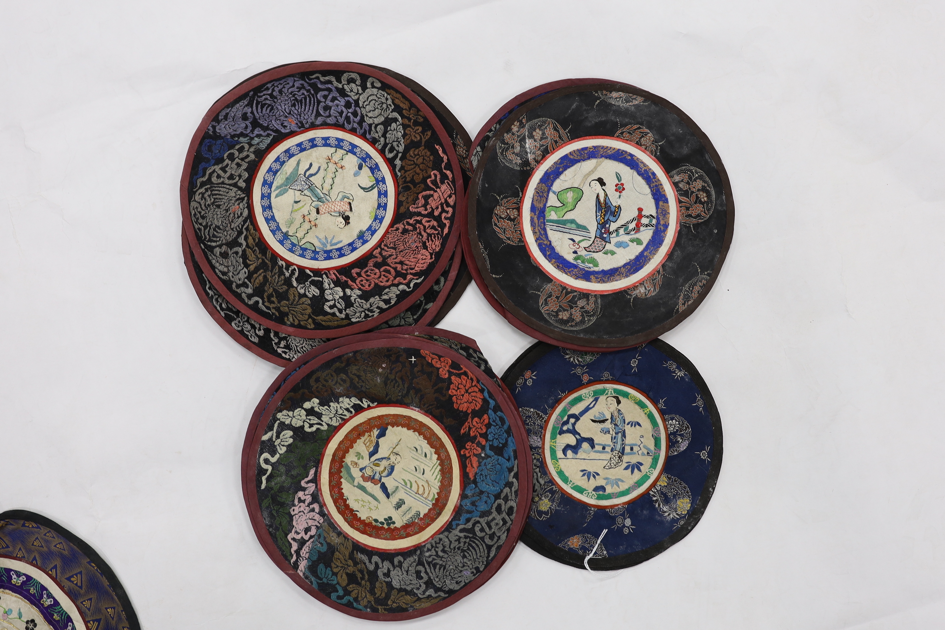 Thirty assorted Chinese silk circular mats, all embroidered with figures, all bordered with silk damask
